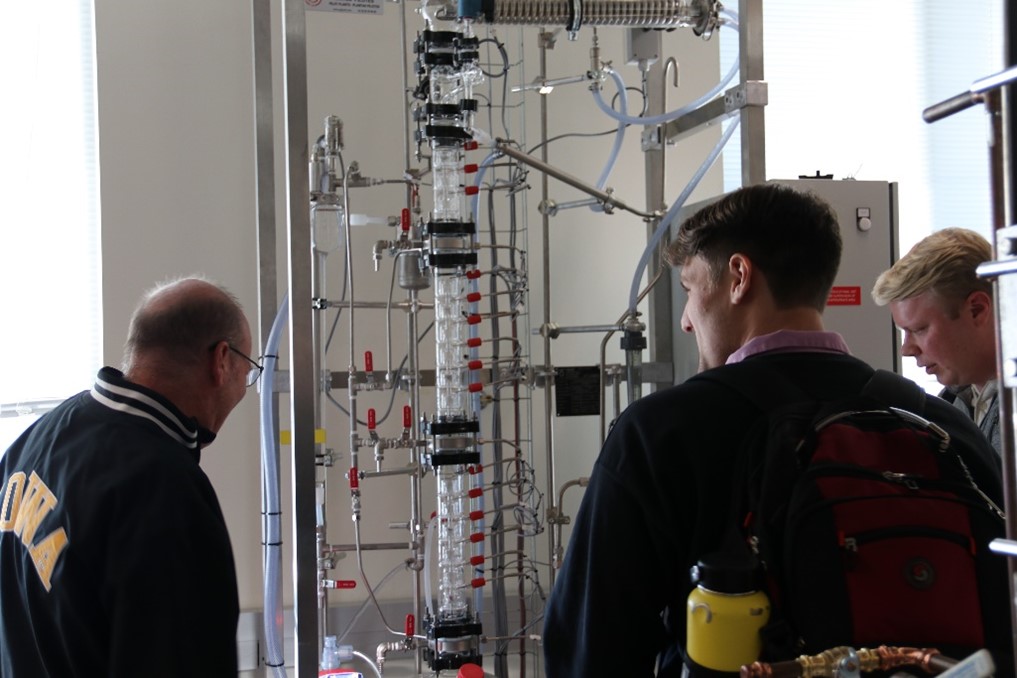 group of people looking at large distillation funnel in chemisty lab