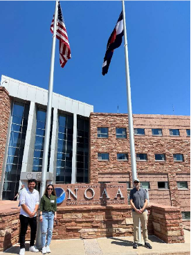 Three people in front of NOAA building