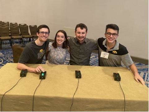 Four people sitting at a table with Jeopardy buttons