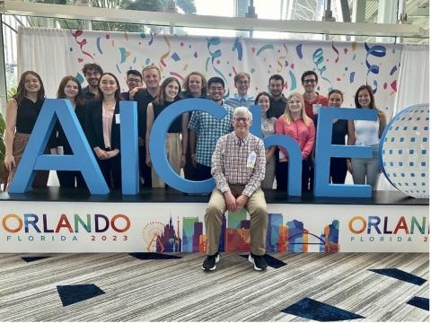 A group of people pose by an AIChE sign