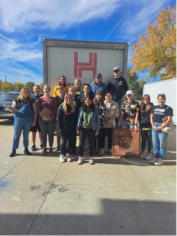 A group posing behind a moving truck