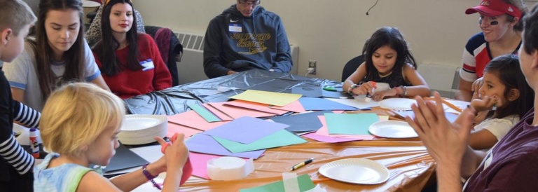 College students help elementary students with art projects