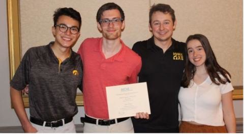 Four students pose with a certificate