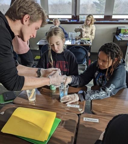 A student leads a group activity with elementary students
