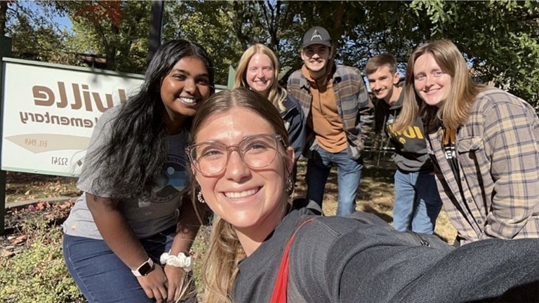 group of students smiling for a selfie outside 