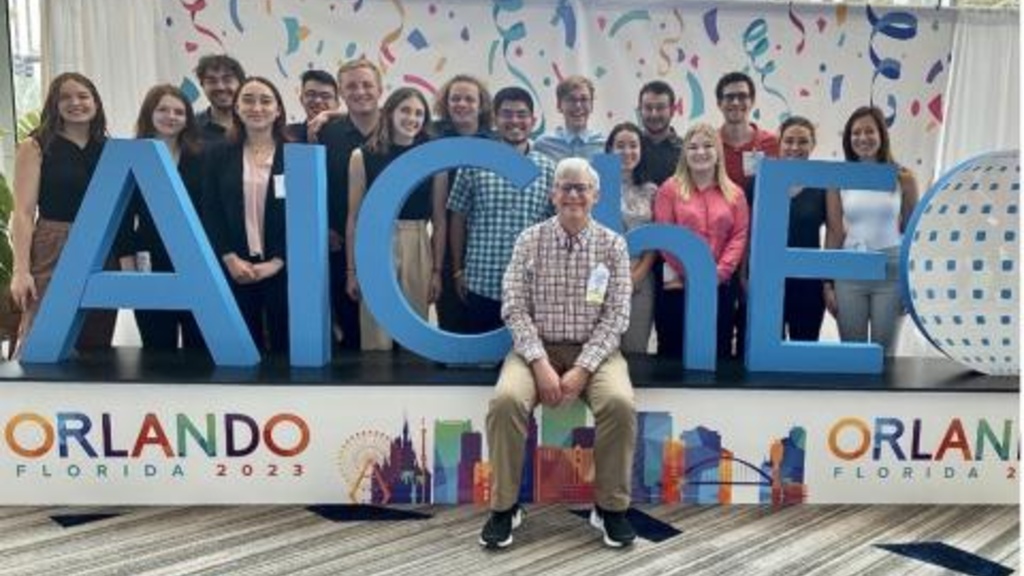 A group of people pose by an AIChE sign